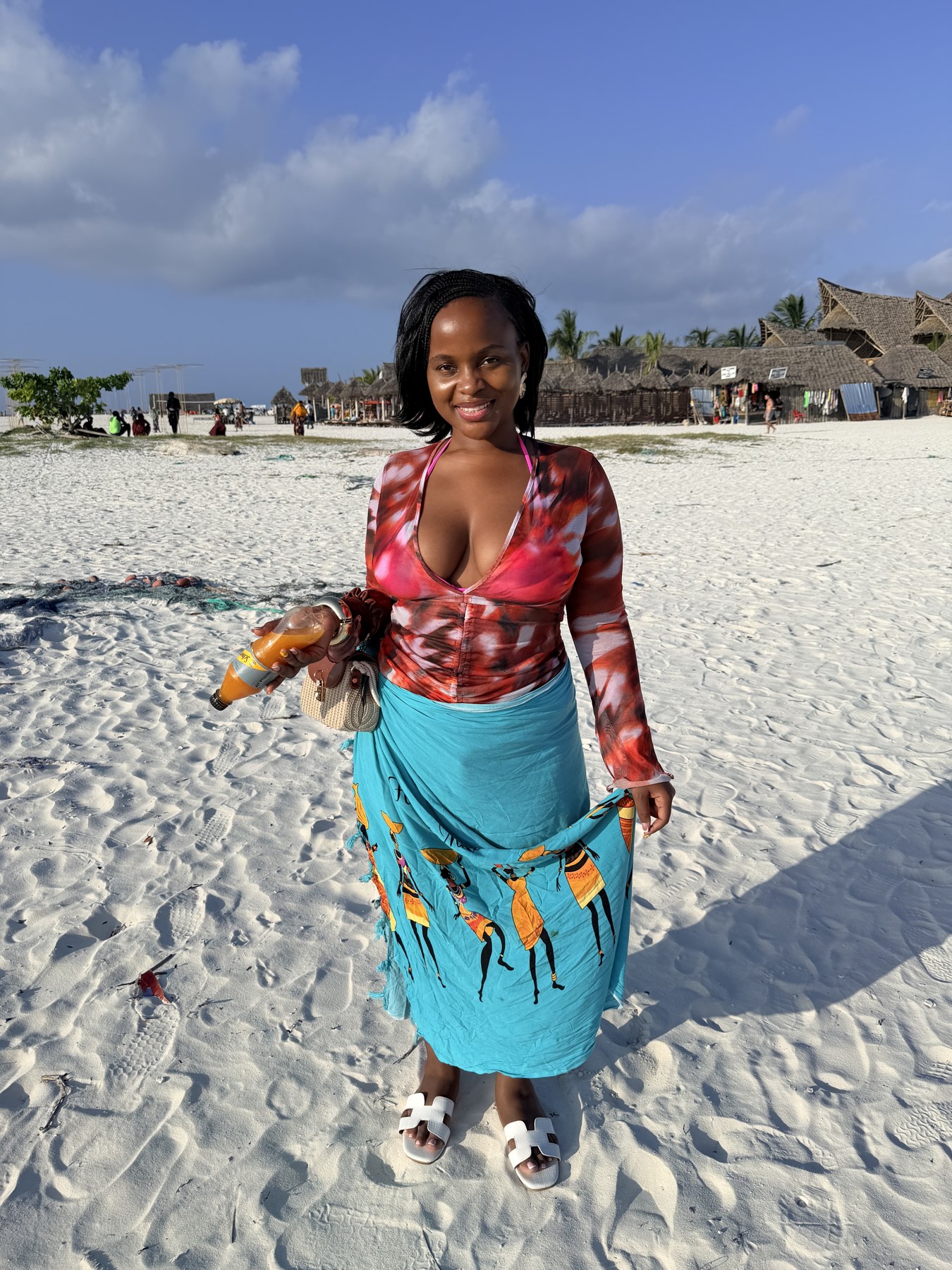 Izuba smiling on the beach in a pink top and turquoise wrap