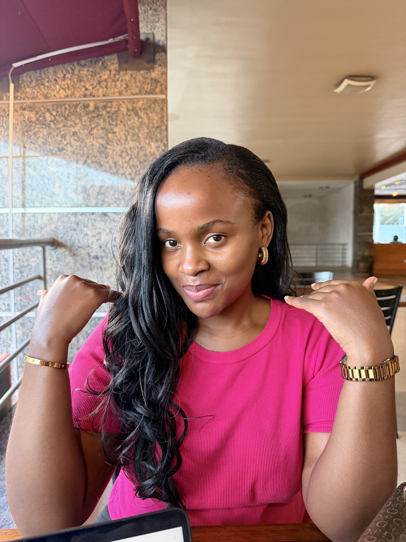 Izuba smiling in a bright pink top at a café